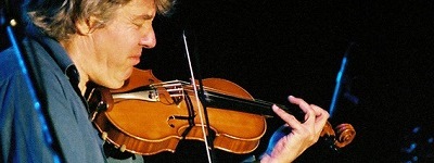 Photographie de Didier Lockwood jouant du violon en concert, les yeux fermés, concentré sur sa musique, son expression est passionnée